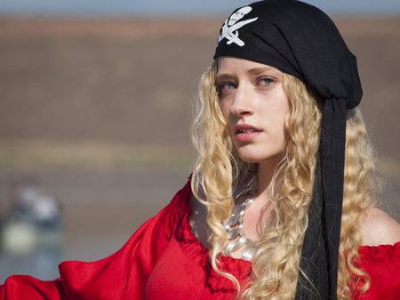 Beautiful young female pirate in red dress.