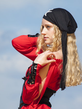 Beautiful young female pirate in red dress.