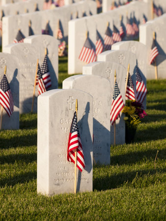 Endless row of white marble gravestones continues above hilltop at the Fort Logan National Cemetery in Denver, Colorado. American flags decorating each grave to mark the Memorial Day.のeditorial素材