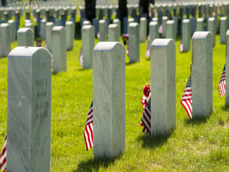 Endless row of white marble gravestones continues above hilltop at the Fort Logan National Cemetery in Denver, Colorado. American flags decorating each grave to mark the Memorial Day.のeditorial素材