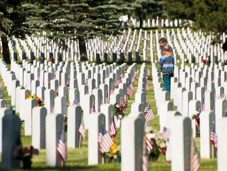 Endless row of white marble gravestones continues above hilltop at the Fort Logan National Cemetery...
