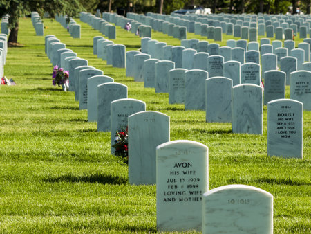 Endless row of white marble gravestones continues above hilltop at the Fort Logan National Cemetery...