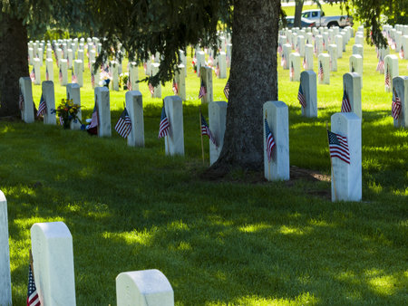 Endless row of white marble gravestones continues above hilltop at the Fort Logan National Cemetery...