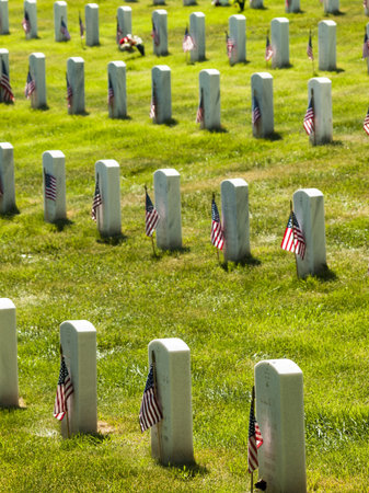 Endless row of white marble gravestones continues above hilltop at the Fort Logan National Cemetery...