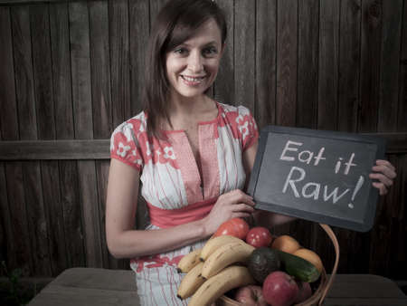 Portrait of a smiling young woman holding vegetables in basket.の写真素材