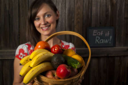 Portrait of a smiling young woman holding vegetables in basket.の写真素材