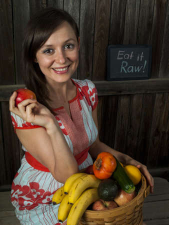 Portrait of a smiling young woman holding vegetables in basket.の写真素材