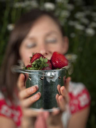 Portrait of a smiling young woman holding strawberries.の写真素材