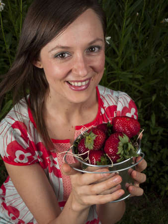 Portrait of a smiling young woman holding strawberries.の写真素材