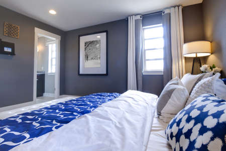 Modern master bedroom with blue wall and white linens.のeditorial素材