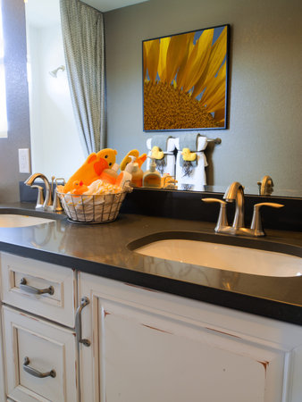 Kids bathroom with yellow ducks decor and white cabinets.のeditorial素材