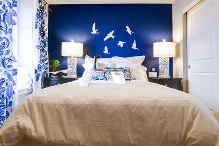 Modern master bedroom with blue wall and white linens.のeditorial素材