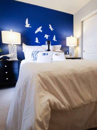 Modern master bedroom with blue wall and white linens.のeditorial素材