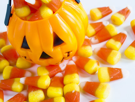 Halloween treat bag filled with candy corn candies on white background.