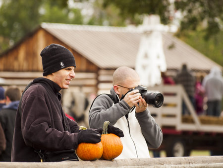 Adults with pumpkins photographing pumpkin patch. 2012 Pumpkin Harvest Festival at Four Mile Historic Park, Denver.のeditorial素材