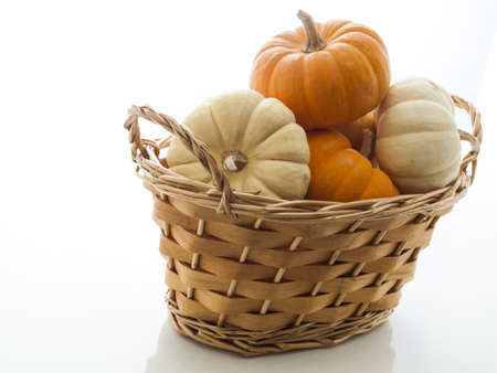 Small orange and white pumpkins in basket on white background.の写真素材