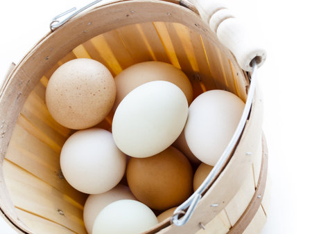 Fresh farm eggs in small basket on white background.
