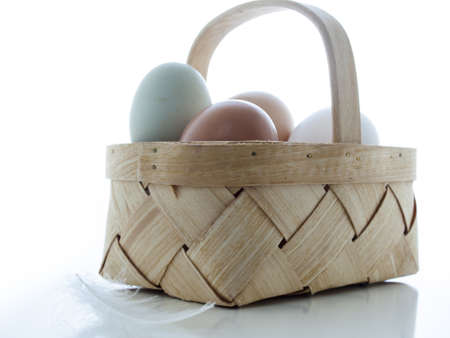 Fresh farm eggs in small basket on white background.の写真素材