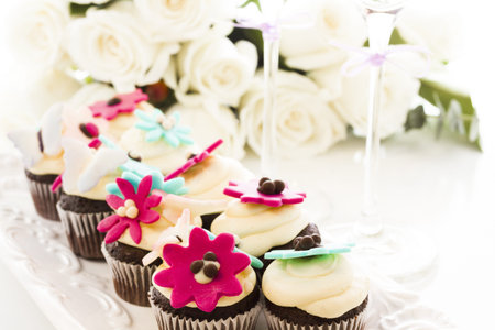 Miniature cupcakes decorated with bright flowers for the wedding party.の写真素材