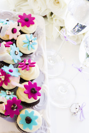 Miniature cupcakes decorated with bright flowers for the wedding party.の写真素材
