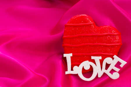 Gourtmet heart shaped cookies decorated for Valentine's Day on pink silk.の写真素材