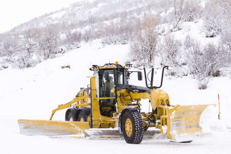 Yellow snowplow clearing rural road from snow.のeditorial素材