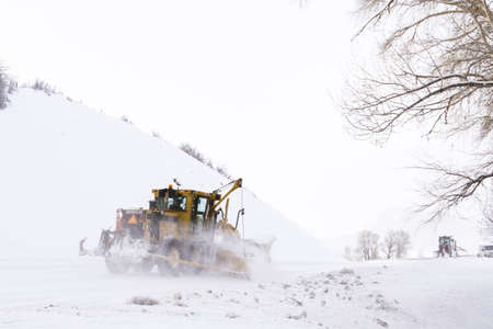 Yellow snowplow clearing rural road from snow.のeditorial素材