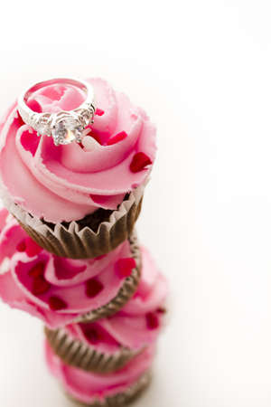 Stack of pink cupcakes with engagement ring on top.の写真素材