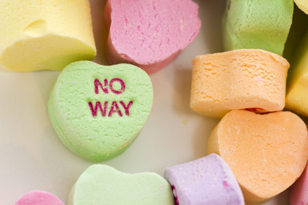 Pile of conversation heart candies on white background.