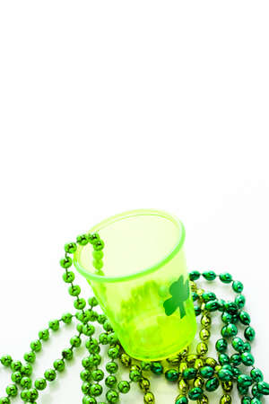 St. Patricks Day beads and shot glass on white background.の写真素材