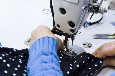 Hands work a sewing machine.