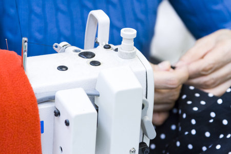 Hands work a sewing machine.