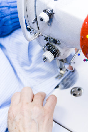 Hands work a sewing machine.