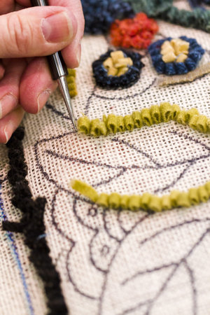 Hands work a hook in hug hooking craft.