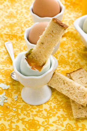 Soft boiled egg in egg cup and served with toast fingers.