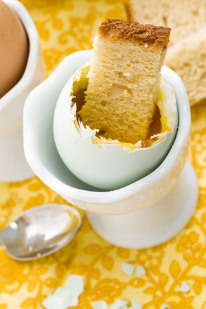 Soft boiled egg in egg cup and served with toast fingers.