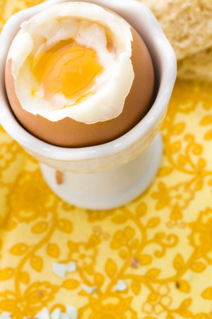 Soft boiled egg in egg cup and served with toast fingers.