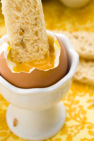 Soft boiled egg in egg cup and served with toast fingers.
