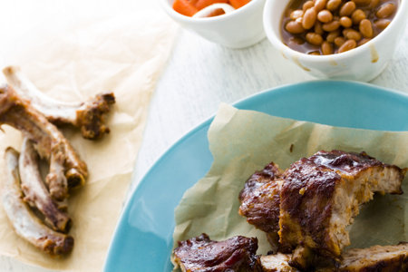 Baby back ribs on the plate with baked beand and fried carrots.の写真素材