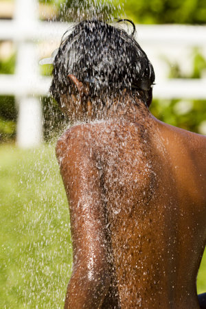 Boy rinsing at the shower after being on the beach.