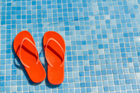 Orange flip flops in the swimming pool.の写真素材