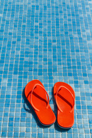 Orange flip flops in the swimming pool.の写真素材