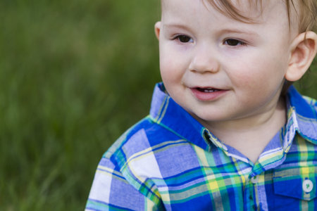 Baby boy sitting on the grass.