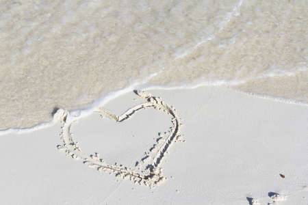 Heart drawing on the beach with wave.の写真素材