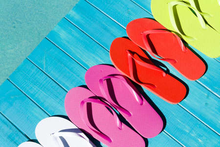 Colorful flip flops by a swimming pool.の写真素材