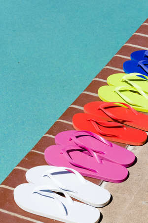 Colorful flip flops by a swimming pool.の写真素材