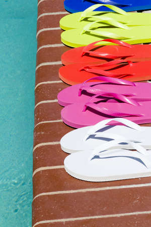 Colorful flip flops by a swimming pool.の写真素材