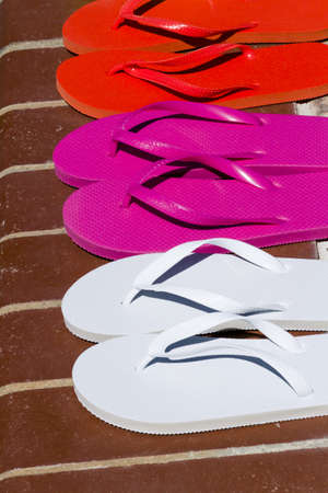 Colorful flip flops by a swimming pool.の写真素材