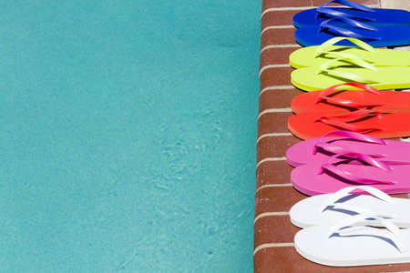 Colorful flip flops by a swimming pool.の写真素材