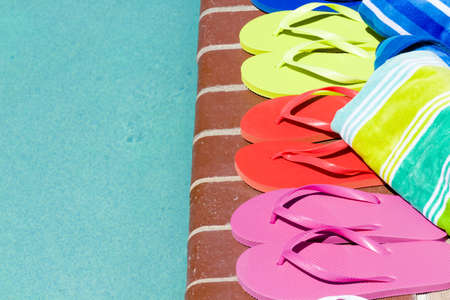 Colorful flip flops by a swimming pool.の写真素材